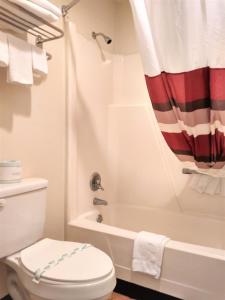a bathroom with a toilet and a tub and a shower at Bastrop Inn in Bastrop