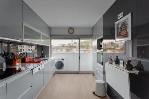 a kitchen with white appliances and a large window at Castelo Point - 2BR Luxe Apartment in the Heart of Guimarães in Guimarães
