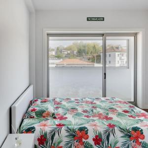 a bedroom with a bed with a floral bedspread and a window at Castelo Point - 2BR Luxe Apartment in the Heart of Guimarães in Guimarães