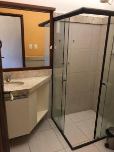 a bathroom with a shower and a sink and a mirror at Linda casa à beira mar in Barra de São Miguel