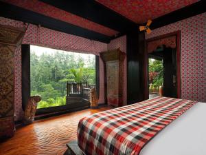 a bedroom with a bed and a large window at Capella Ubud, Bali in Ubud