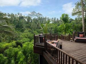 a wooden deck with a couch and a view of the forest at Capella Ubud, Bali in Ubud
