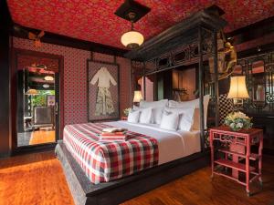 a bedroom with a large bed and a red wall at Capella Ubud, Bali in Ubud