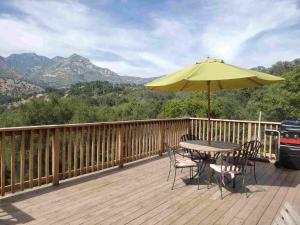 una mesa y sillas en una terraza con sombrilla en Alta Peak Vista en Three Rivers