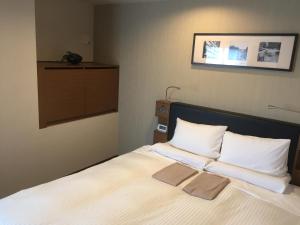 a bedroom with a large bed with white sheets and pillows at HOTEL MYSTAYS Kamata in Tokyo