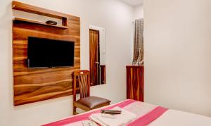 a bedroom with a bed and a tv and a chair at Hotel Plaza Executive - near BKC in Mumbai