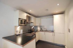 a kitchen with white cabinets and a black counter top at SIAC Barbican Farringdon in London