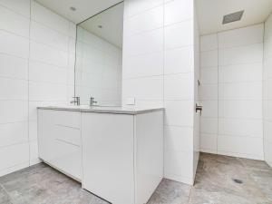 Baño blanco con lavabo y espejo en Aqua Mist Penthouse en Port Fairy