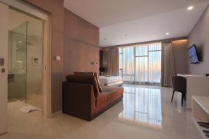 a living room with a brown couch and a bedroom at Grand Whiz Megamas Manado in Manado