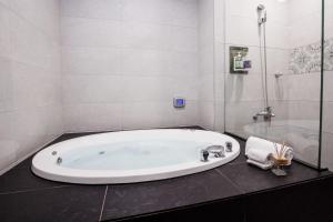 a white bathroom with a tub and a shower at Duo Romance Hotel in Hualien City