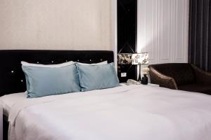 a bedroom with a bed with blue pillows and a chair at Duo Romance Hotel in Hualien City