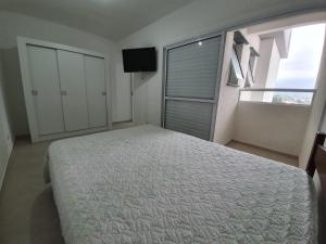 a bedroom with a bed and a large window at Condomínio completo em Ubatuba a 300 metros da praia in Ubatuba +33 photos