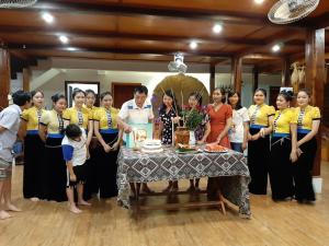 grupa ludzi stojących przy stole z tortem w obiekcie Mai Chau Dreams Homestay w mieście Mai Châu