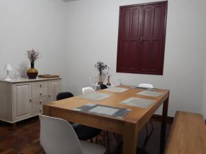 a dining room with a wooden table and white chairs at Casa Vermelha in Ouro Preto