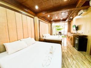 1 dormitorio con 1 cama blanca grande y TV en Kaiyana Boracay Beach Resort, en Boracay