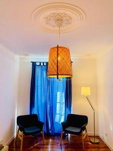 a living room with two chairs and a chandelier at Best Apartment in Paços de Arcos in Paço de Arcos