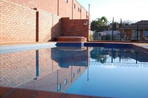 a brick building with a pool of water next to it at Australian Settlers Motor Inn in Swan Hill
