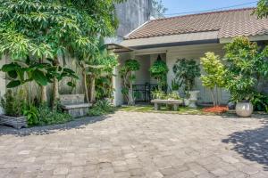 une maison dotée d'une cour avec un banc et des arbres dans l'établissement RedDoorz Syariah near Taman Pelangi Jogja 2, à Yogyakarta