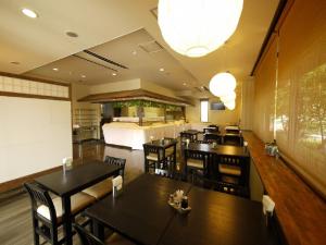 a restaurant with tables and chairs and a bed at Hotel Route-Inn Court Minami Matsumoto in Matsumoto