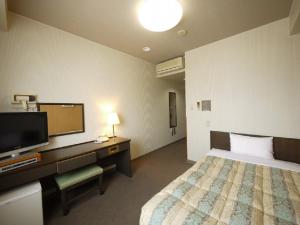 松本市にあるホテルルートインコート南松本のベッド、デスク、テレビが備わるホテルルームです。