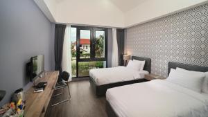 a hotel room with two beds and a television at The Nichehome Waterside Living in Chiang Mai