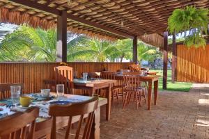 a restaurant with wooden tables and chairs and palm trees at Casa Corveta in São Miguel do Gostoso