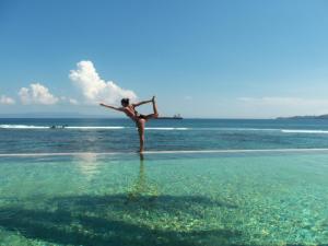 a woman standing in the water on a beach at Sea Breeze Candidasa in Candidasa