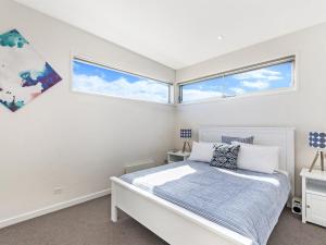 Un dormitorio con una cama y dos ventanas. en 38 Oceane, en Port Fairy