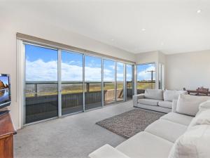 a living room with white furniture and large windows at 38 Oceane in Port Fairy