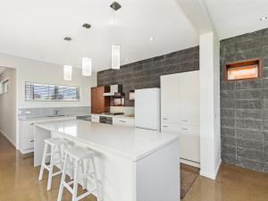 a kitchen with white cabinets and a white refrigerator at 38 Oceane in Port Fairy