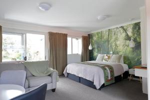 Un dormitorio con una cama, un sofá y una silla. en Aden Motel, en Te Anau