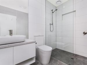 a white bathroom with a toilet and a sink at Aqua Mist Seascape in Port Fairy