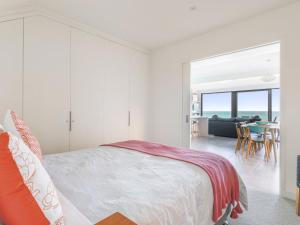 a white bedroom with a bed and a living room at Aqua Mist Seascape in Port Fairy