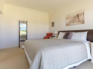 a bedroom with a large white bed and a mirror at Amhurst Cottage in Port Fairy