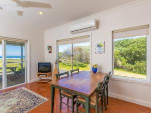 a dining room with a table and chairs and windows at Amhurst Cottage in Port Fairy