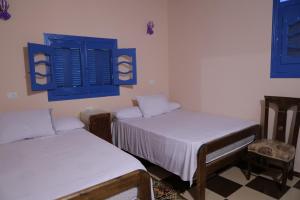 two beds in a room with blue shuttered windows at Tunis Village Chalet in Fayoum Center