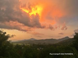 Pua Tranquil Vista Homestay في بوا: إطلالة على غروب الشمس مع الجبال في الخلفية
