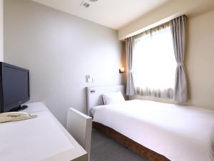 a hotel room with two beds and a television at Hotel Wing International Himeji in Himeji