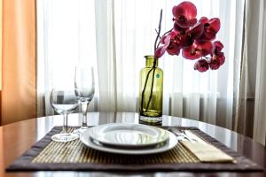 una mesa con un plato y dos vasos y un jarrón con flores en Hotel Azia, en Perm