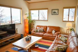 a living room with leather couches and a tv at Holiday Home Nozawa in Nozawa Onsen