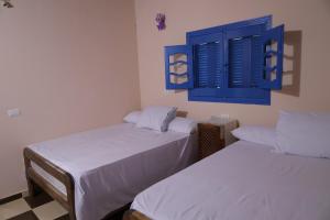 duas camas num quarto com persianas azuis em Tunis Village Chalet em Fayum