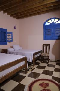 Habitación con 2 camas, ventana y suelo a cuadros. en Tunis Village Chalet, en El Fayum