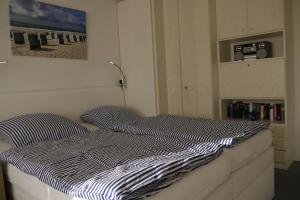 - un lit avec une couette à rayures bleue et blanche dans une chambre dans l'établissement Bollmann, à Westerland