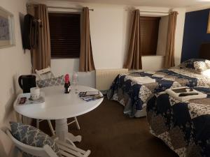 une chambre d'hôtel avec une table et deux lits dans l'établissement Bed And Blueberry, à Douglas