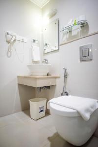 a white bathroom with a toilet and a sink at Abad Green Forest Thekkady in Thekkady