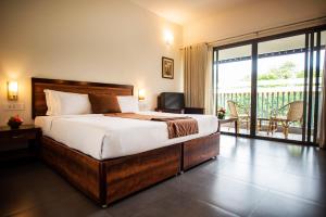 a bedroom with a large bed and a balcony at Abad Green Forest Thekkady in Thekkady +67 photos