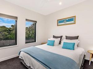 a bedroom with a large bed with two windows at Chimneys On Bank in Port Fairy