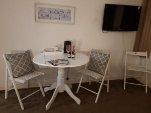 einen weißen Tisch mit 2 Stühlen und einen TV in der Unterkunft Blueberry Two Bedroom Suite in Douglas