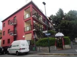 a white van parked in front of a red building at Hotel Renato in Sesto San Giovanni