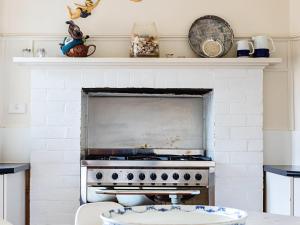 a kitchen with a white brick fireplace with a stove at Dingle On Barclay in Port Fairy
